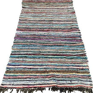 May include: A multi-colored striped rug made from recycled fabric. The rug has a fringe on the bottom edge.