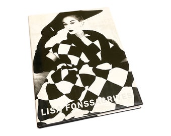 May include: Black and white photo book cover featuring a woman wearing a black and white chequered dress and a black hat. The title of the book is "LISA FONSSAGRIVES".