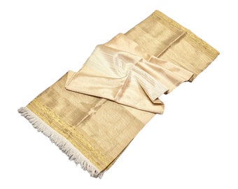 Op de afbeelding: Een beige gebedskleed met een gefranst randje en een gouden bies. Het kleed is dubbelgevouwen en heeft een zijdezachte textuur.