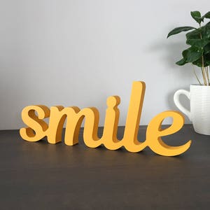 Segno di legno positivo 'sorriso' dipinto in giallo, o colore di vostra scelta. Segno di legno della casa felice, segno dello spazio di lavoro dell'ufficio del sorriso, segno dell'umore felice