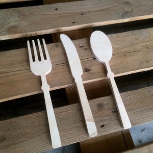 May include: A set of three wooden utensils, a fork, knife, and spoon, on a wooden surface.