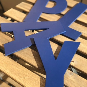 May include: Blue wooden letters spelling out the word "PLAY" on a wooden surface.