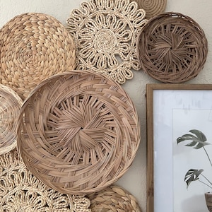 May include: A collection of woven wall decor in various shapes and sizes, featuring natural brown and beige tones. The decor includes round, circular, and starburst shapes, all made from woven materials.