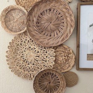 May include: A collection of woven wall decor in various shapes and sizes. The decor is made of natural materials and has a light brown colour.