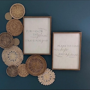 May include: Two framed inspirational quotes with a blue background. The top quote reads "For I know the plans I have for you." The bottom quote reads "Plans to give you hope and a future."  The quotes are surrounded by a decorative arrangement of woven straw circles.