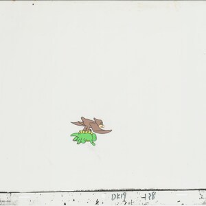May include: A brown bird with yellow eyes is flying while perched on the back of a green turtle.