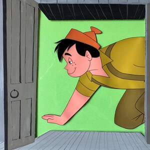 Puede incluir: Una obra de arte de papel recortado en capas que representa a un personaje de dibujos animados con cabello negro y gorro naranja, vistiendo una camisa amarilla, asom&aacute;ndose por una puerta abierta sobre un fondo verde lima y suelo gris.