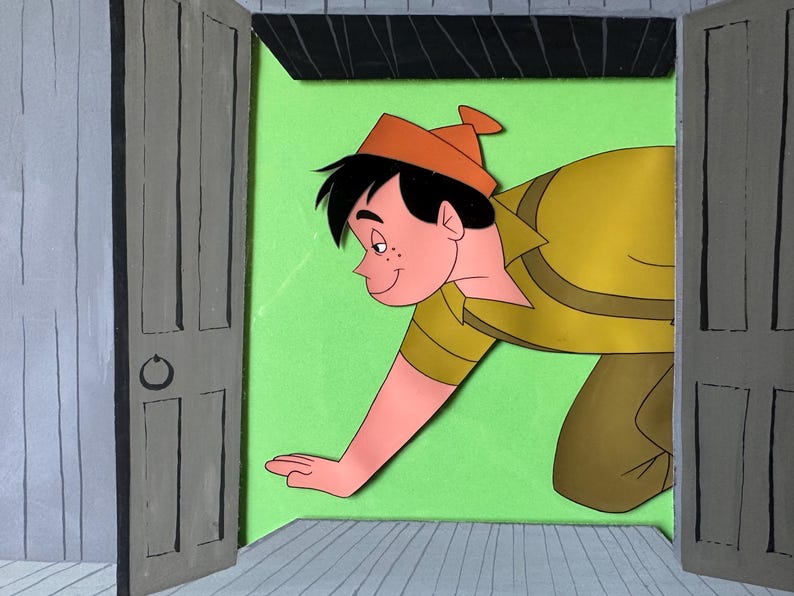 Puede incluir: Una obra de arte de papel recortado en capas que representa a un personaje de dibujos animados con cabello negro y gorro naranja, vistiendo una camisa amarilla, asom&aacute;ndose por una puerta abierta sobre un fondo verde lima y suelo gris.