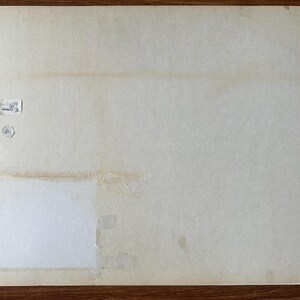 Puede incluir: Un soporte de papel rectangular de color blanco roto con una textura lisa y envejecida. La superficie presenta una peque&ntilde;a etiqueta rectangular blanca con texto impreso, un sello circular y un gran parche cuadrado blanco fijado con cinta adhesiva.