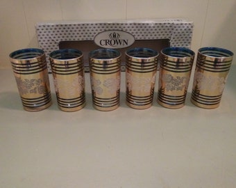 Pode incluir: Conjunto de seis copos de vidro dourado e azul com um design floral. Os copos estão na sua caixa original, que diz "Crown".