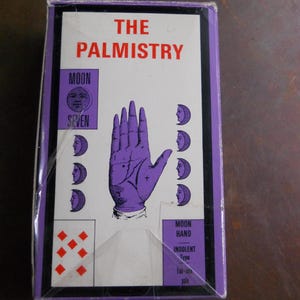 May include: A purple and white card with the text "THE PALMISTRY" in red. The card features a hand with a palm reading chart and the text "MOON HAND INDOLENT Type Fair-skin pale".