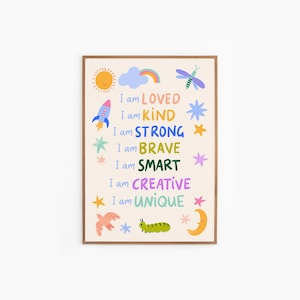 May include: A framed art print with a cream background and colorful illustrations. The print features a sun, rainbow, rocket, stars, bird, caterpillar, and moon. Text reads "I am LOVED, KIND, STRONG, BRAVE, SMART, CREATIVE, UNIQUE."