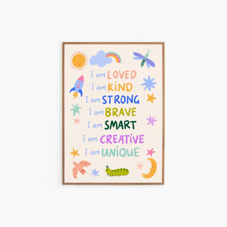 May include: A framed art print with a cream background and colorful illustrations. The print features a sun, rainbow, rocket, stars, bird, caterpillar, and moon. Text reads "I am LOVED, KIND, STRONG, BRAVE, SMART, CREATIVE, UNIQUE."