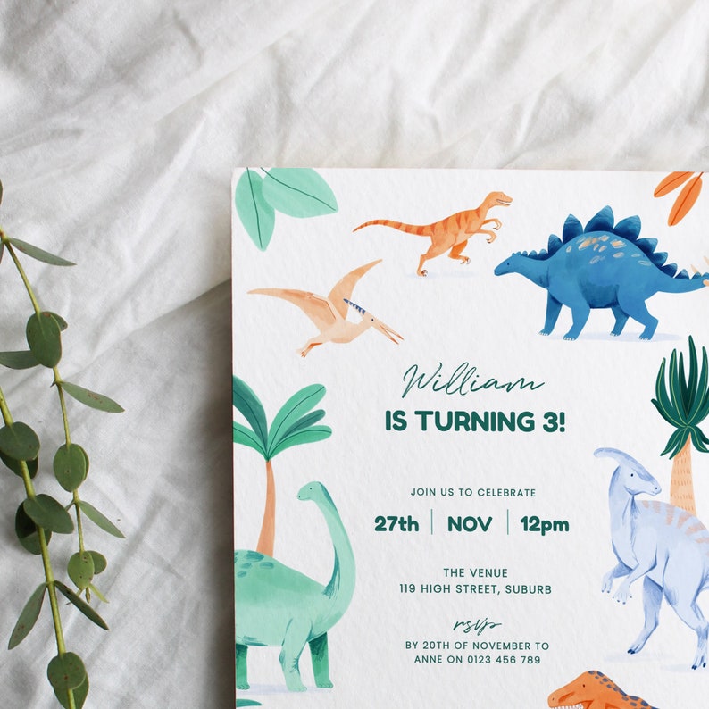 May include: A white invitation card with watercolor illustrations of various dinosaurs and palm trees. The text reads "William IS TURNING 3!" and includes event details: date, time, and venue. The invitation has a playful and colorful design.