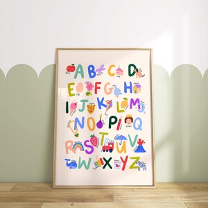 May include: A framed alphabet poster with colorful illustrations. Each letter is paired with a corresponding image, such as an apple for A, a cake for C, and a zebra for Z. The poster is in a wooden frame and is displayed on a wall.