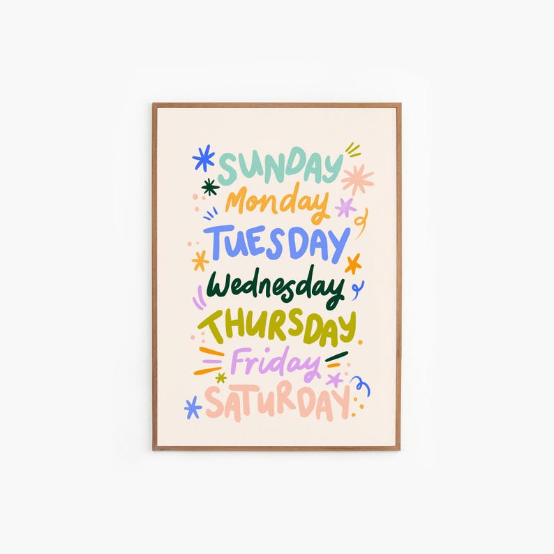 May include: A framed art print featuring the days of the week in colorful, whimsical lettering. Each day is written in a different color, with decorative starbursts and accents. The days are arranged vertically on a cream-colored background.