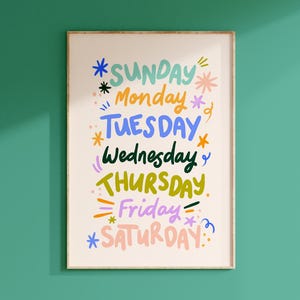 May include: A framed art print featuring the days of the week in a colorful, whimsical design. Each day is written in a different color, with decorative stars and squiggles. The words are in a playful, handwritten style, perfect for a home or office.