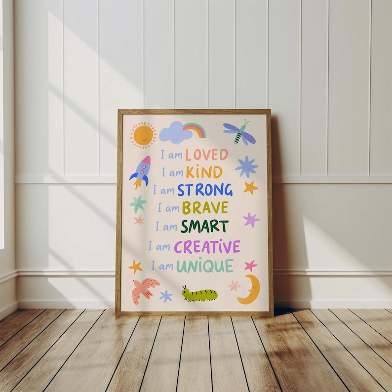 May include: A framed art print with the words "I am LOVED, KIND, STRONG, BRAVE, SMART, CREATIVE, UNIQUE" in colorful text. The print features illustrations of a sun, rocket, cloud, rainbow, dragonfly, stars, bird, caterpillar, and moon.
