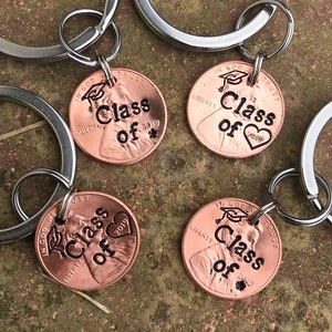 May include: Four copper penny keychains with the words "Class of 2019" engraved on them. Each keychain has a graduation cap and a heart design.