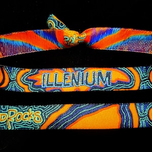 May include: A colorful woven wristband with the text "ILLENIUM" in white lettering on a black background. The wristband has a blue, orange, and green pattern.