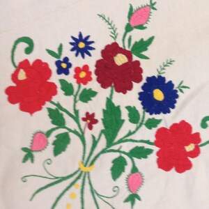 K&ouml;nnte beinhalten: Gestickte Blumenmuster auf wei&szlig;em Stoff mit roten, rosa, blauen, gelben und gr&uuml;nen Blumen. Das Design umfasst eine Vielzahl von Blumenformen und -gr&ouml;&szlig;en und schafft ein optisch ansprechendes und komplexes Muster.
