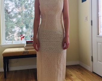 May include: A white sleeveless dress with a lace pattern. The dress has a fitted bodice and a straight skirt.