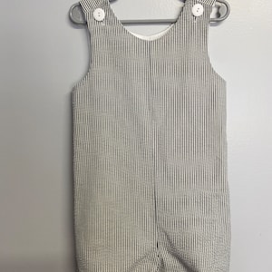 May include: White and black striped baby overalls with white buttons.