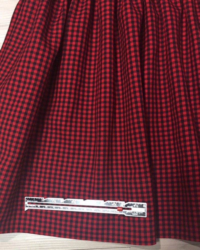 May include: Red and black gingham fabric with a white ruler measuring 3 1/2 inches.