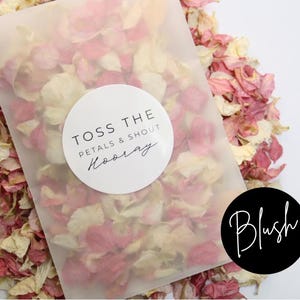 Puede incluir: Una bolsa de pl&aacute;stico transparente llena de p&eacute;talos de flores rosas y blancas. La bolsa tiene una pegatina circular blanca con el texto "Toss the petals & shout Hooray". Una pegatina circular negra con el texto "Blush" est&aacute; en la esquina inferior derecha.