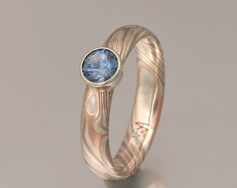 Puede incluir: Un anillo de plata con una piedra preciosa azul engastada en un engaste de bisel. La banda está hecha de metal estampado.