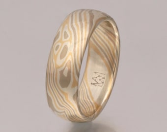 May include: A gold and silver patterned wedding band with a subtle swirl design. The band is engraved with the initials "MW".