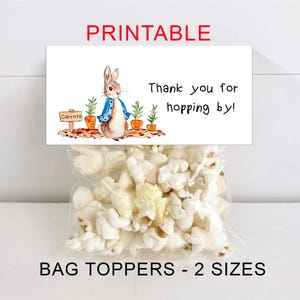 Puede incluir: Una bolsa de plástico transparente llena de palomitas de maíz, cubierta con una tarjeta blanca que dice "PRINTABLE" y "Thank you for hopping by!" con una ilustración de un conejo. La tarjeta también dice "BAG TOPPERS - 2 SIZES".