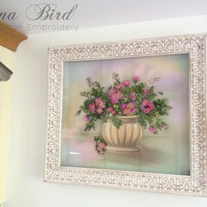 May include: A white framed picture featuring a pink and green floral arrangement in a beige pot. The picture is titled "Inna Bird Silk Ribbon Embroidery".