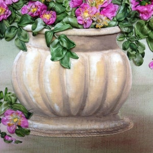 May include: A white ceramic vase with a ribbed design, filled with pink silk flowers and green leaves.