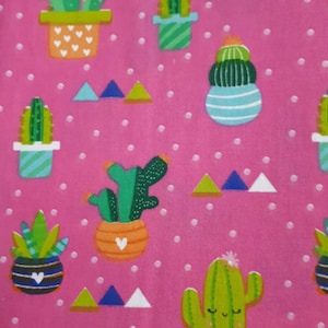 Peut inclure: Un tissu rose avec un motif répété de cactus verts dans des pots. Les pots sont décorés de rayures, de cœurs et d'autres motifs. De petits pois blancs et des triangles colorés complètent le design.