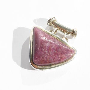 Peut inclure: Un pendentif en argent avec une pierre précieuse rose triangulaire. Le pendentif a une bélière en argent avec une boucle pour attacher une chaîne.