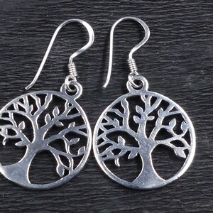 May include: A pair of silver earrings featuring a tree of life design. The earrings are made from sterling silver and have a delicate, intricate design.