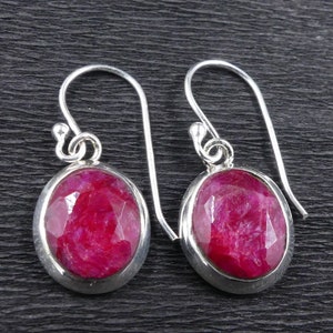 Op de afbeelding: Een paar zilveren oorbellen met ovale rode robijn edelstenen.