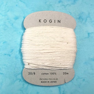 May include: A spool of white cotton thread labeled "KOGIN 20/8 cotton 100% 20m daruma-ito.co.jp MADE IN JAPAN"