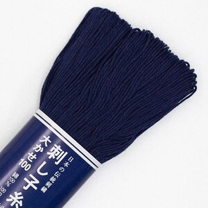 May include: A skein of dark navy blue embroidery floss. The floss is tightly wound and wrapped with a label featuring Japanese text. The label indicates the floss is 100% cotton.