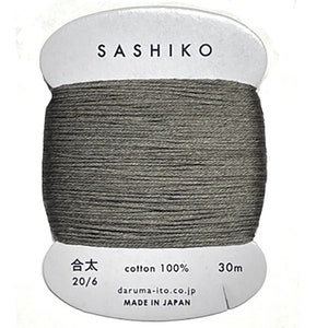 May include: A spool of gray Sashiko thread, made of 100% cotton. The label reads "Sashiko", "20/6", "cotton 100%", "30m", "daruma-ito.co.jp", and "MADE IN JAPAN".