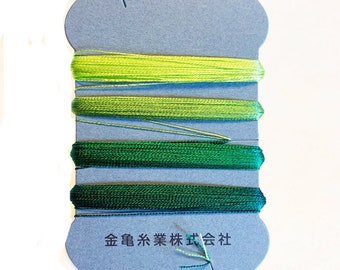 May include: A blue card with several spools of green embroidery floss. The floss shades range from light to dark green. The card has Japanese text at the bottom.
