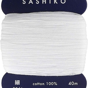 May include: A spool of white cotton thread labeled "SASHIKO" with the text "cotton 100%", "20/4", "40m", "daruma-ito.co.jp", and "MADE IN JAPAN".
