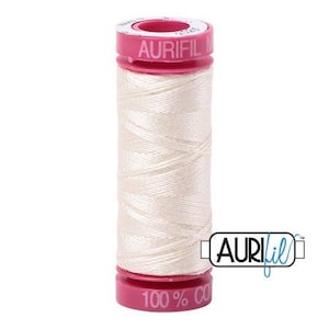 May include: A spool of Aurifil thread, featuring a white thread wrapped around a cylindrical core. The spool has pink caps at the top and bottom, with the brand name and thread composition printed on them. The thread is 100% cotton.