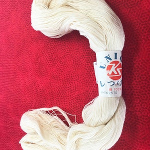 May include: A skein of white cotton thread with a label that reads "UNIC しつけ糸 綿 100% Y-TK 2570".