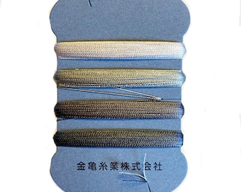 May include: A spool of thread in shades of gray and blue. The thread is wound around a blue cardboard backing. The text "金亀糸業株式会社" is printed on the bottom of the card.
