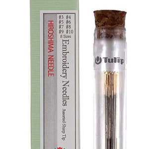 May include: A glass jar with a cork top containing a set of 8 Tulip embroidery needles in assorted sizes. The jar is labeled "Tulip" and the box it comes in is green with the text "Hiroshima Needle Embroidery Needles Assorted Sharp Tip" and "Tulip Made in Japan".
