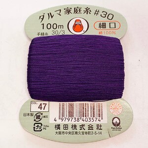 May include: A spool of purple thread labeled "ダルマ家庭糸 #30" (Daruma Family Thread #30) with the text "100m 細口" (100m Fine Mouth) and "手縫糸 30/3" (Hand Sewing Thread 30/3) and "綿100%" (Cotton 100%). The label also includes a barcode and the text "横田株式会社" (Yokota Co., Ltd.) and "大阪市中央区南久宝寺町2-5-14" (Minami Kyuboji-cho 2-5-14, Chuo-ku, Osaka).