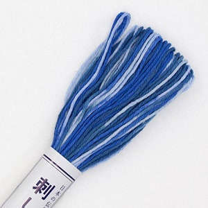 May include: A skein of blue, white, and light blue embroidery floss. The floss is wound around a white cardboard spool with the Japanese text "刺しゅう糸" printed on it, which translates to "embroidery thread".