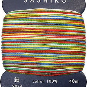 May include: A spool of colorful Sashiko thread, made of 100% cotton. The thread is 20/4 weight and 40 meters long. The label reads "Sashiko", "cotton 100%", "20/4", "40m", "daruma-ito.co.jp", and "MADE IN JAPAN".